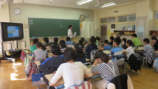 小学校での環境学習出前授業。市職員が教壇に立ち、地球温暖化のメカニズムや温暖化の影響について説明をしたあと、子どもたちによるグループディスカッションの時間も取った。