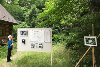 門の目の前には管理棟が建つ。公開日には、会員が撮影した四季折々の写真をパネルにして掲示し、緑地の自然や生物を紹介している。（狛江市提供）