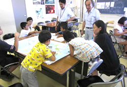 写真：作業中、机に身を乗り出して地図に書き込む子も…