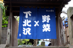 ママンカ市場を開催する毎月第4日曜日に提げられている『下北沢×野菜』と大書した藍色の暖簾