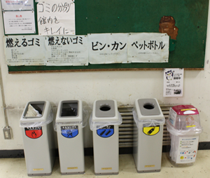 サークル棟になっている10号館の玄関ホールに並ぶ分別ボックス。その一番端に、キャップ回収ボックスも置かれている。