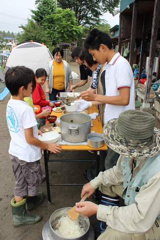 園庭にテーブルを出して、子どもたちが一人ずつ食器を持って並ぶ。