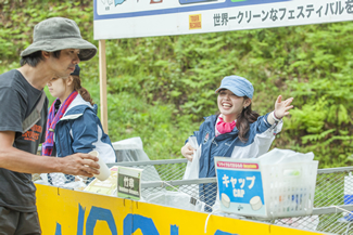 自然豊かな会場で、来場者にごみ分別を呼びかけるボランティア。