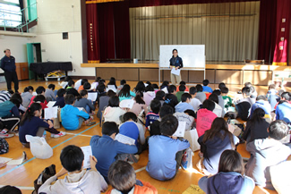 収穫祭のこの日、等々力小学校の5年生3クラスが体育館に集まって、講師の小野寺ひかるさんの話を聞いて、『田んぼから生まれたものが、人の暮らしを支えながら自然界に還っていく様子』を学んだ。