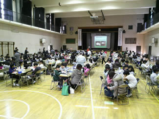 体育館の中で、模型キットづくりの工作（足立区立弥生小学校の出前授業にて）。