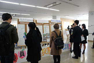 カーボンオフセットの取り組みについて紹介するつばさ総合高校ISO委員会の展示。クレジット購入先候補となる3つの団体をアピールし、投票を呼びかけるメンバーたち。