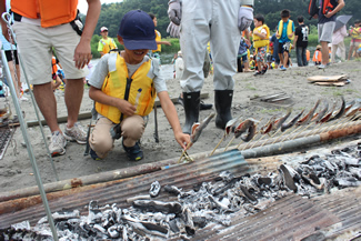 竹串に刺した魚がずらりと並ぶ光景は壮観だ。炭火から放射される熱は予想以上に熱く、近寄れないと顔をしかめる子もいる。