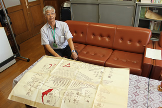 真鯛の骨格図を広げて紹介する、学校長の橋浦義之先生（中野区立中野本郷小学校　校長室にて）。