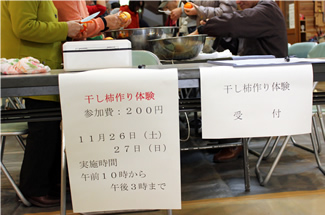 奥多摩湖畔にある山のふるさと村のクラフトセンターの入り口ホールで実施された「干し柿づくり体験」。10数年続いている、毎年恒例のイベントだ。
