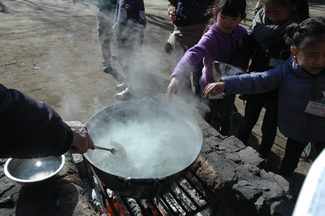 炊きあがったおかゆに、刻んだ若葉を入れる。